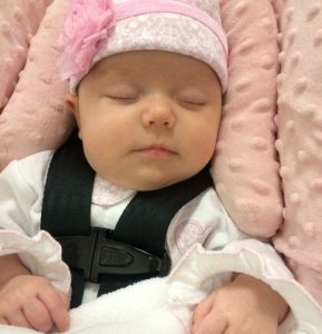 baby sleeping in a pink car seat