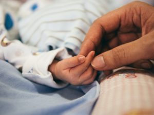child in hospital holding a parent's hand