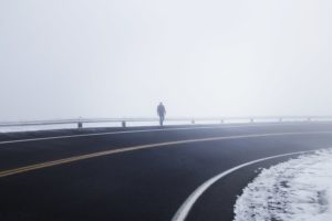 person on the shoulder of a foggy highway