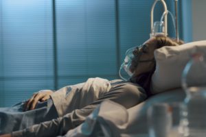 Mujer tendida en la cama de un hospital con una máscara de oxígeno
