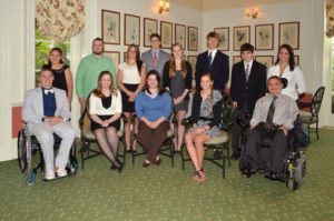 Group of scholarship winners sitting and standing in a room