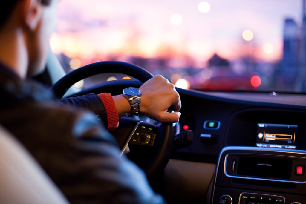 Hombre conduciendo coche al atardecer