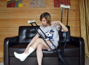 woman sitting on a couch in crutches