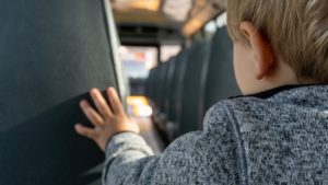 niño pequeño caminando en el autobús escolar