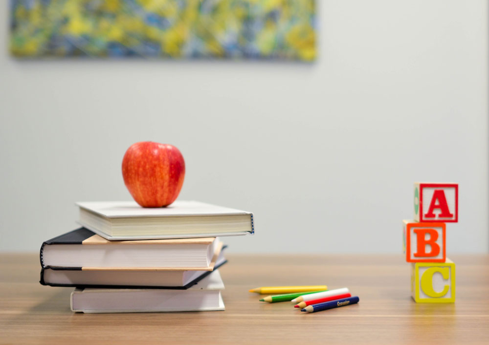 Útiles escolares y una manzana sentada en un escritorio de madera