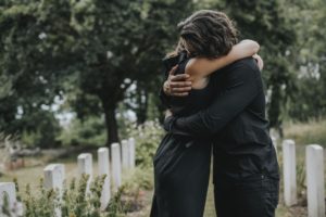 pareja consolándose unos a otros en un cementerio