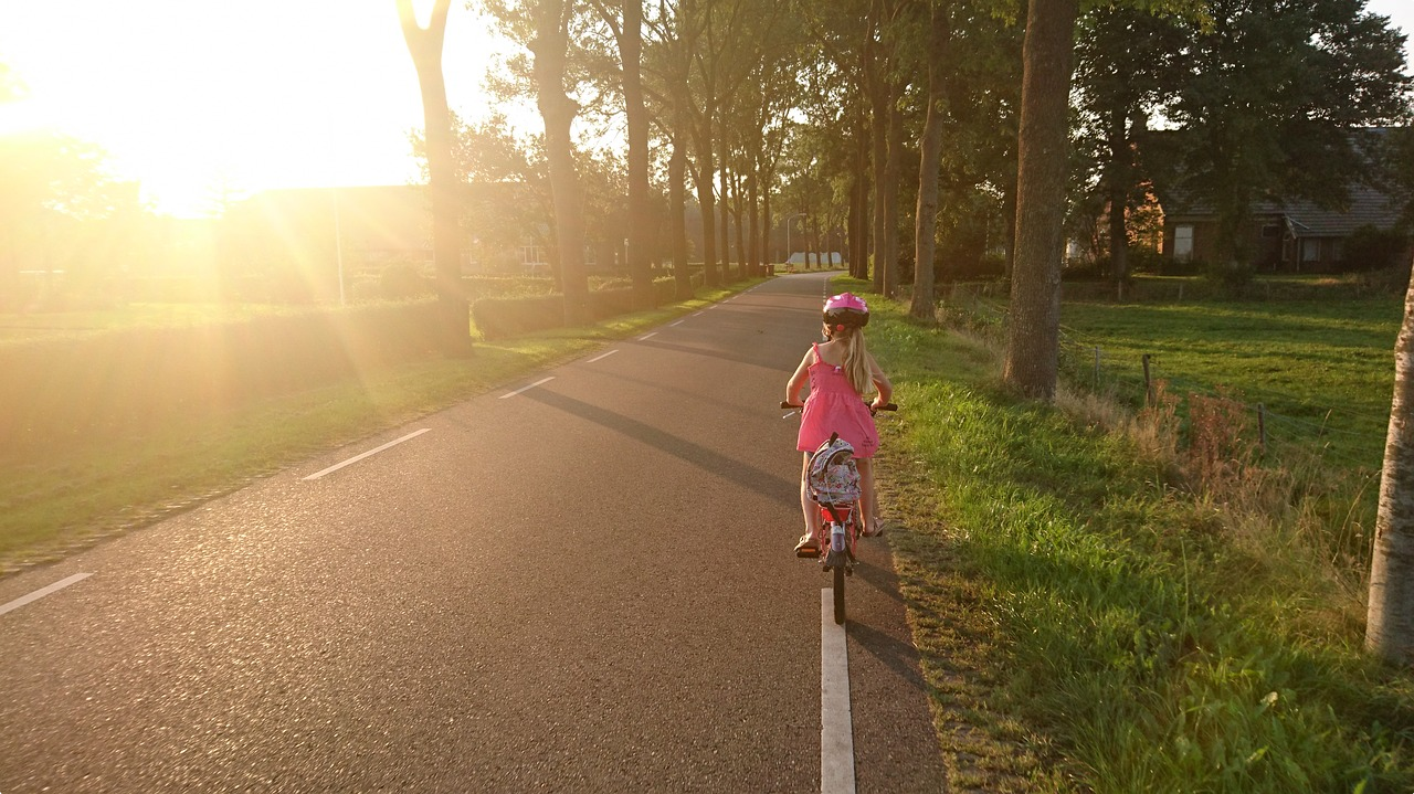 Young girl riding bike on side of road