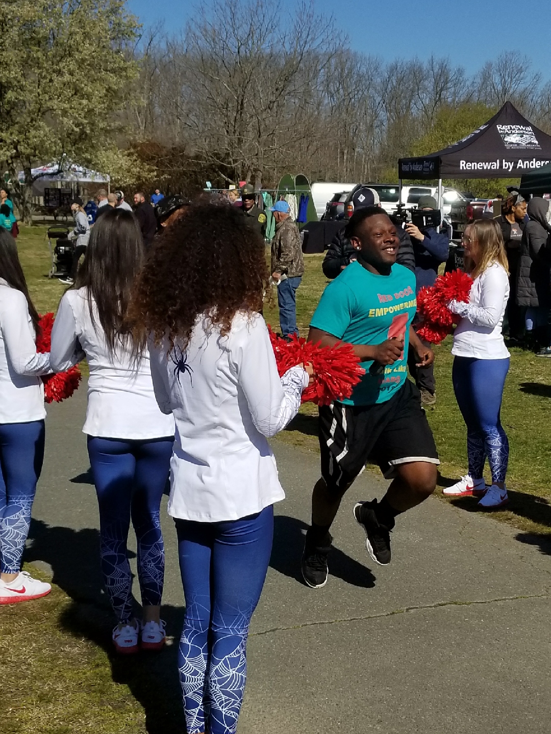 Boy running while cheerleaders cheer him on with pompoms