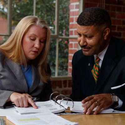 Woman pointing to paper in a binder with man looking at it