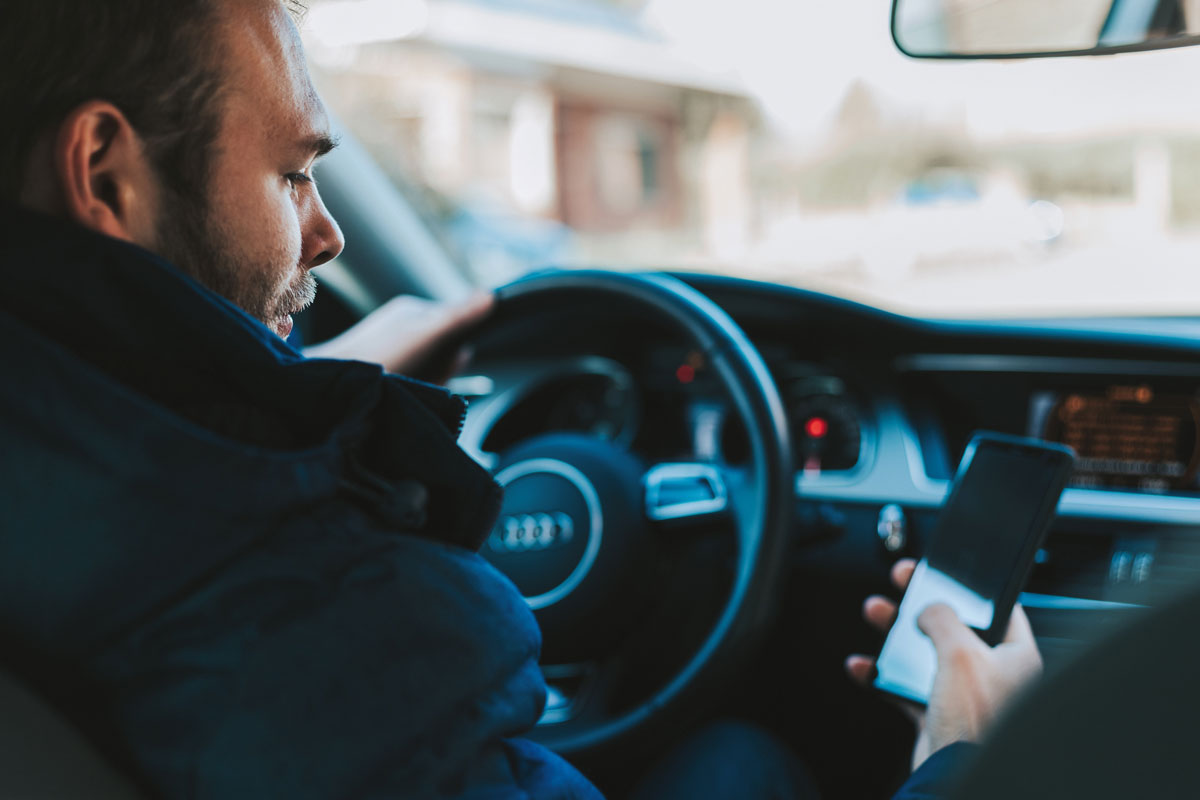 Hombre enviando mensajes de texto mientras conduce