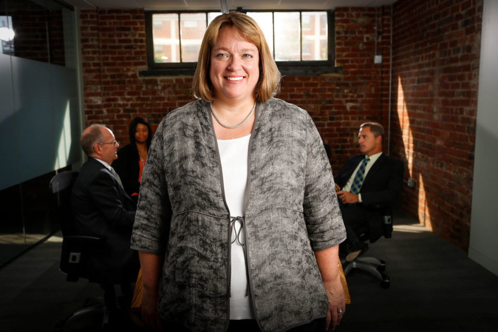 Courtney Allen Van Winkle smiling with people speaking in background at table