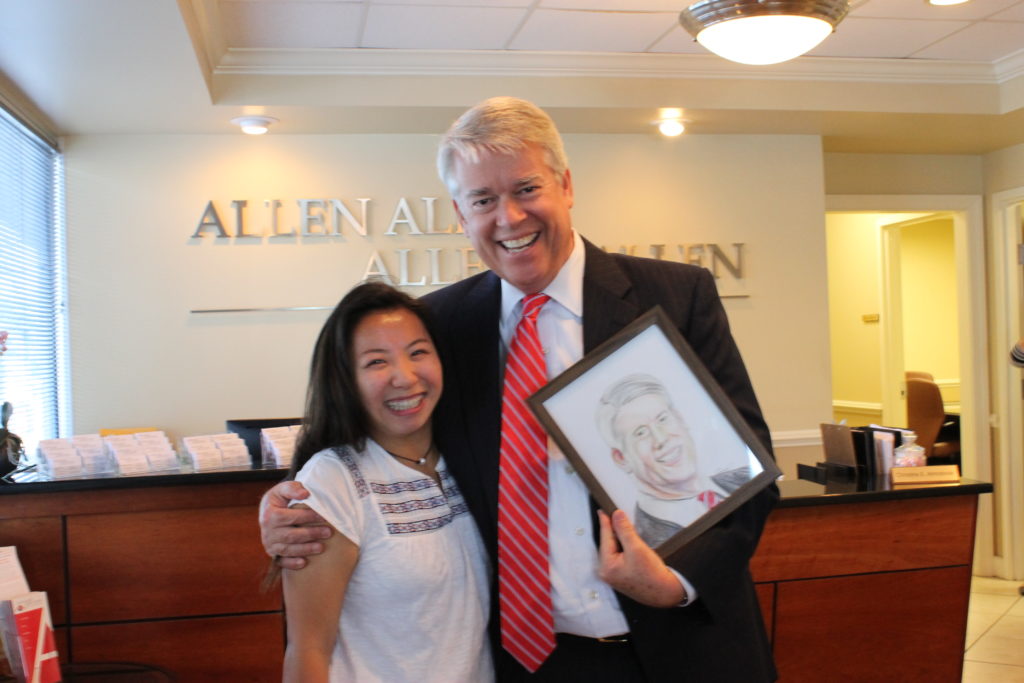 Man and woman smiling with framed drawing of the man