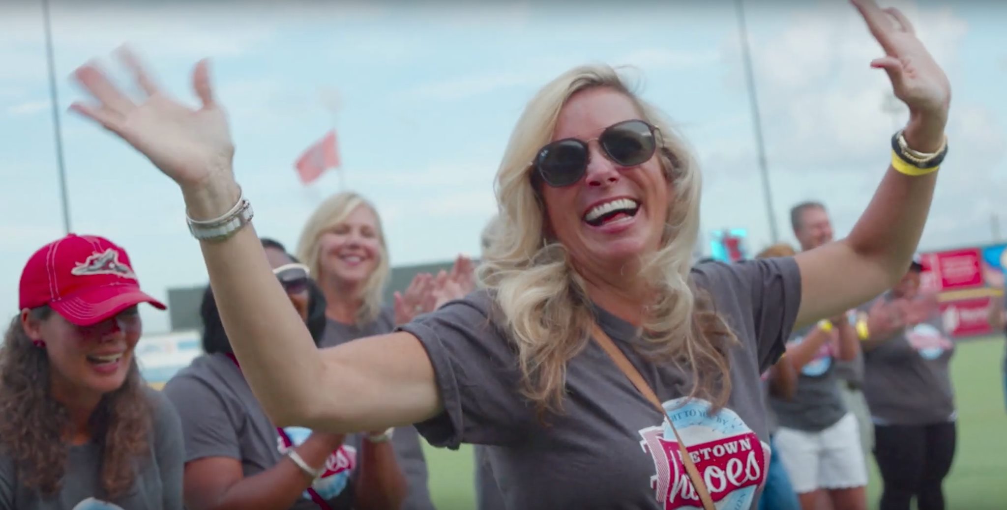 Woman smiling with hands up while wearing Hometown Heroes shirt