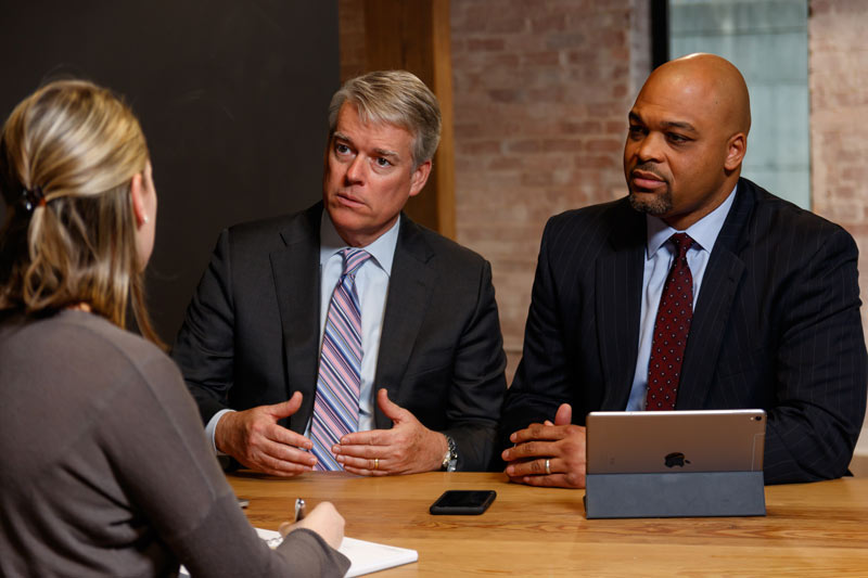 Two men speaking to woman at a table