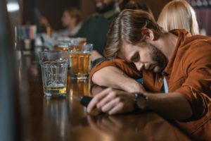 Hombre borracho descansando la cabeza en la barra con las llaves del coche