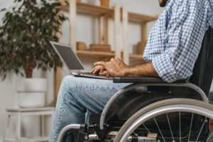 Hombre discapacitado en silla de ruedas en la computadora portátil