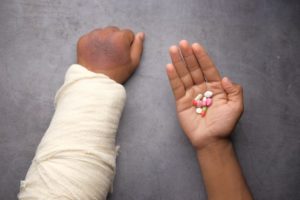 injured person in a cast holding pills