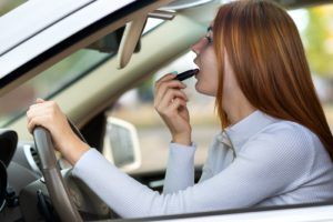 teen putting on lipstck while driving
