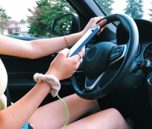 adolescente usando un teléfono celular mientras conduce