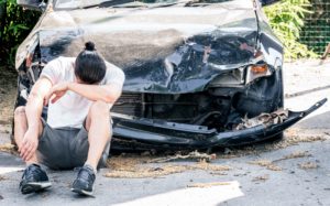 Hombre llorando delante de su coche dañado tras un accidente
