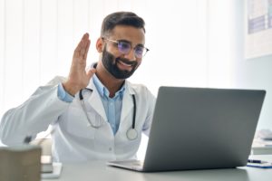 teledoctor waving at a computer screen