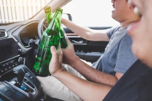 two men drunk driving clinking bottles