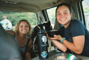 Dos chicas comiendo y bebiendo en el auto.