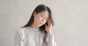 Mujer asiática con dolor de cabeza