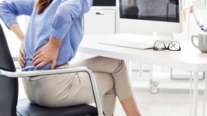 mujer en su escritorio experimentando dolor de espalda