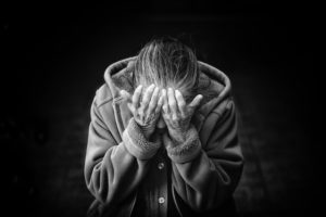 anciana con la cabeza entre las manos, que sufre de demencia