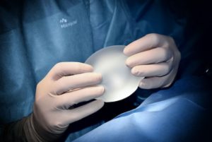 Doctor sosteniendo implantes mamarios de solución salina