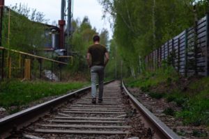 man walking on railroad tracks