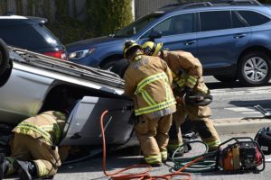 deadly crash , paramedics pulling out person in flipped car on the road