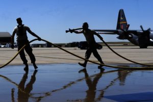 militares limpian con manguera una pista de aterrizaje en una base de la Fuerza Aérea