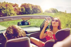 teens blowing bubbles in a speeding convertible