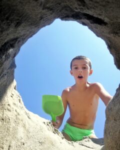 Chico cavando un hoyo de arena en la playa.