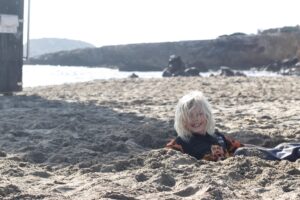 blonde child sitting in a sand hole