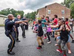 Officers dancing with children in the middle of the street for National Night Out