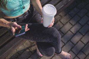 persona bebiendo una taza de café para llevar