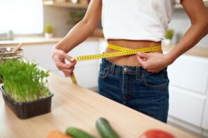woman measuring her waist in the kitchen
