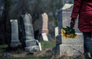 Persona deprimida dejando flores para una víctima de suicidio en el cementerio