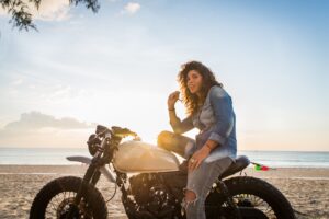 Mujer en motocicleta en la playa.