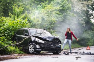 Una joven loca frente a su auto destrozado