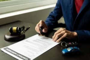 Lawyer stamping a contract document with a gavel, car keys, and toy car on the desk.