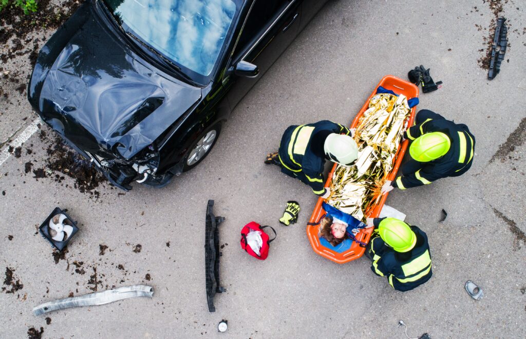 Bomberos y personal de emergencias asisten a un conductor herido en una camilla tras un grave accidente de tráfico.