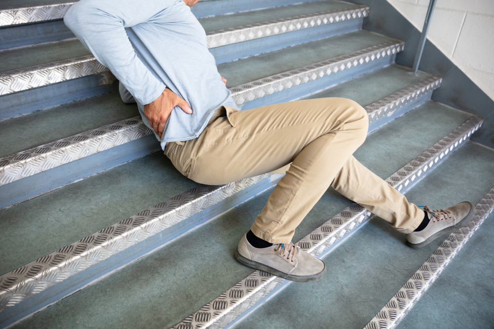Hombre maduro tendido en las escaleras tras resbalar y caer.