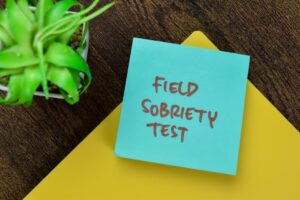Concept of Field Sobriety Test write on sticky notes isolated on Wooden Table.
