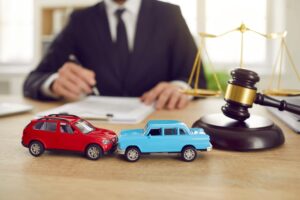 Close up of two toy model cars on background of judge who is conducting lawsuit in car accident.
