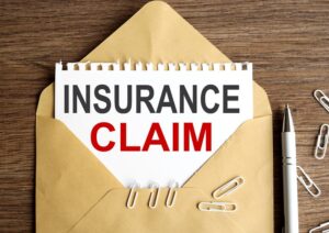 insurance claim, text on white notepad paper on wood background ON craft envelope