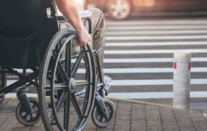 Disabled man on wheelchair preparing to cross the road on pedestrian crossing